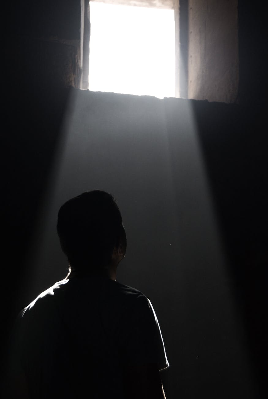 man in a cell looking at light coming from a window