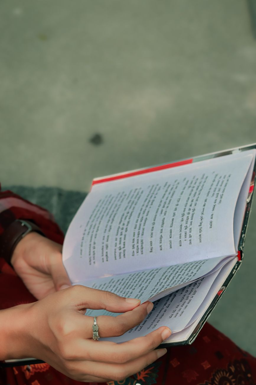young adult reading a book outdoors in khulna