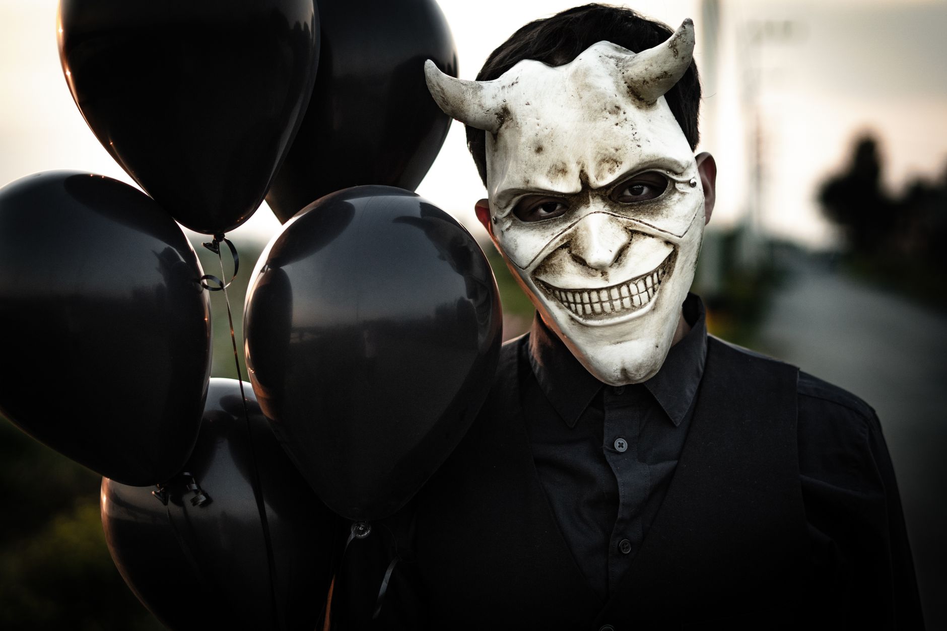 man in a mask with black balloons