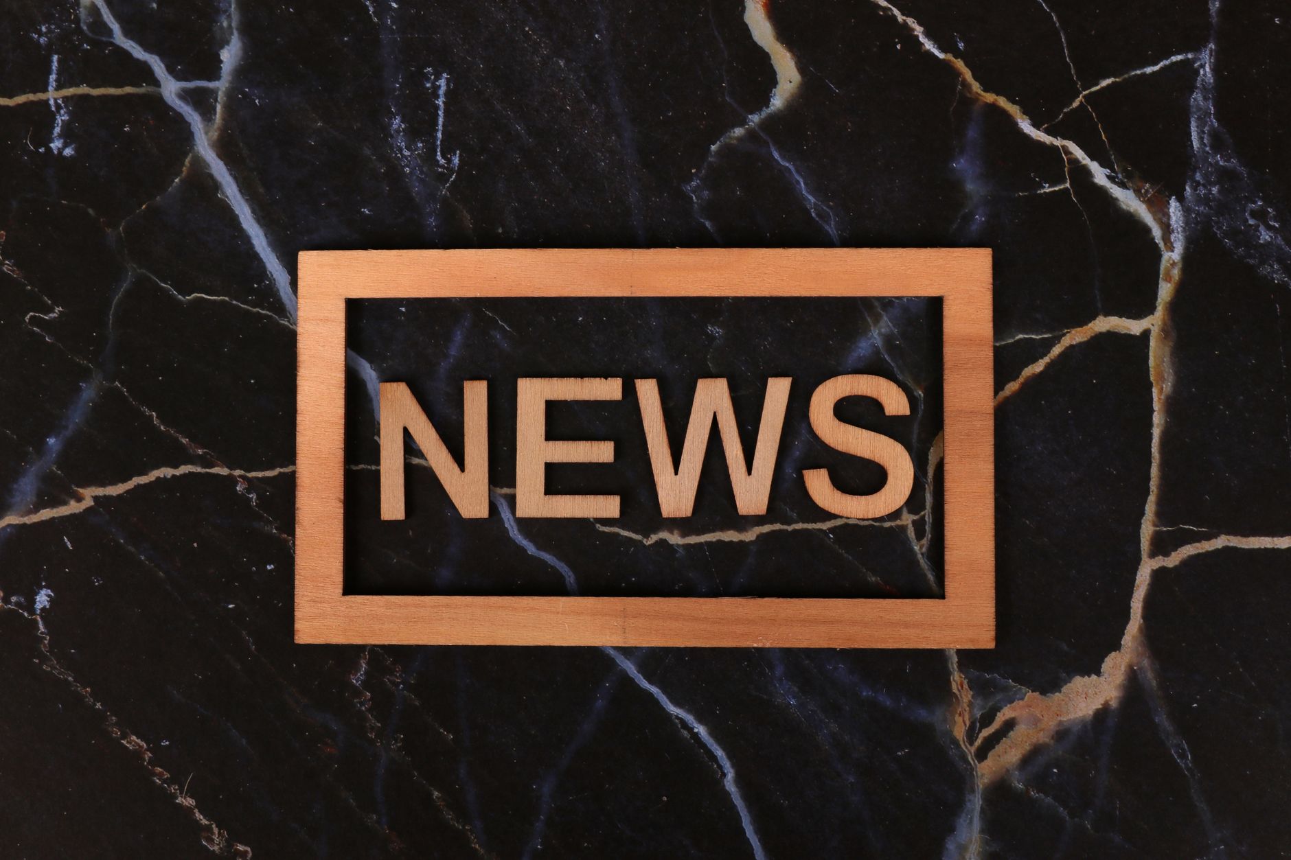 wooden news sign on dark marble background